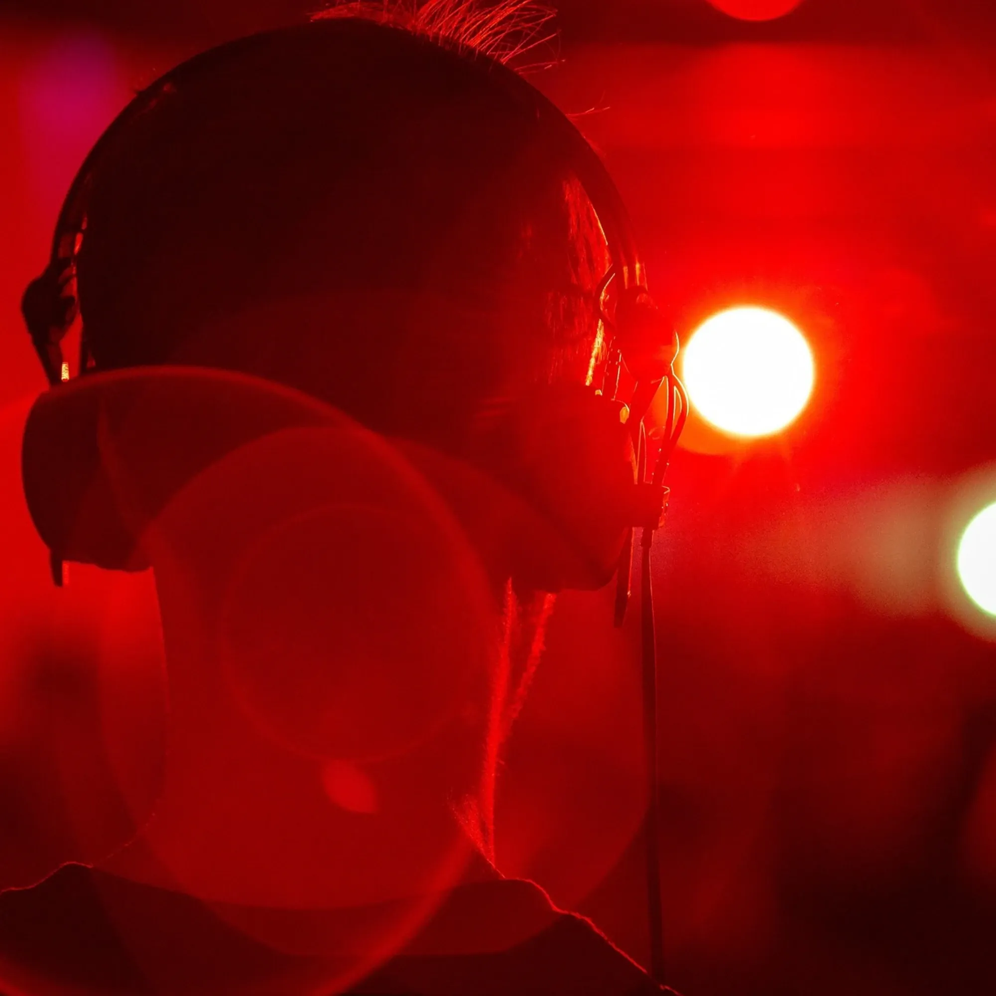 person wearing headphones bathed in dramatic red lighting, representing digital audio advertising technology