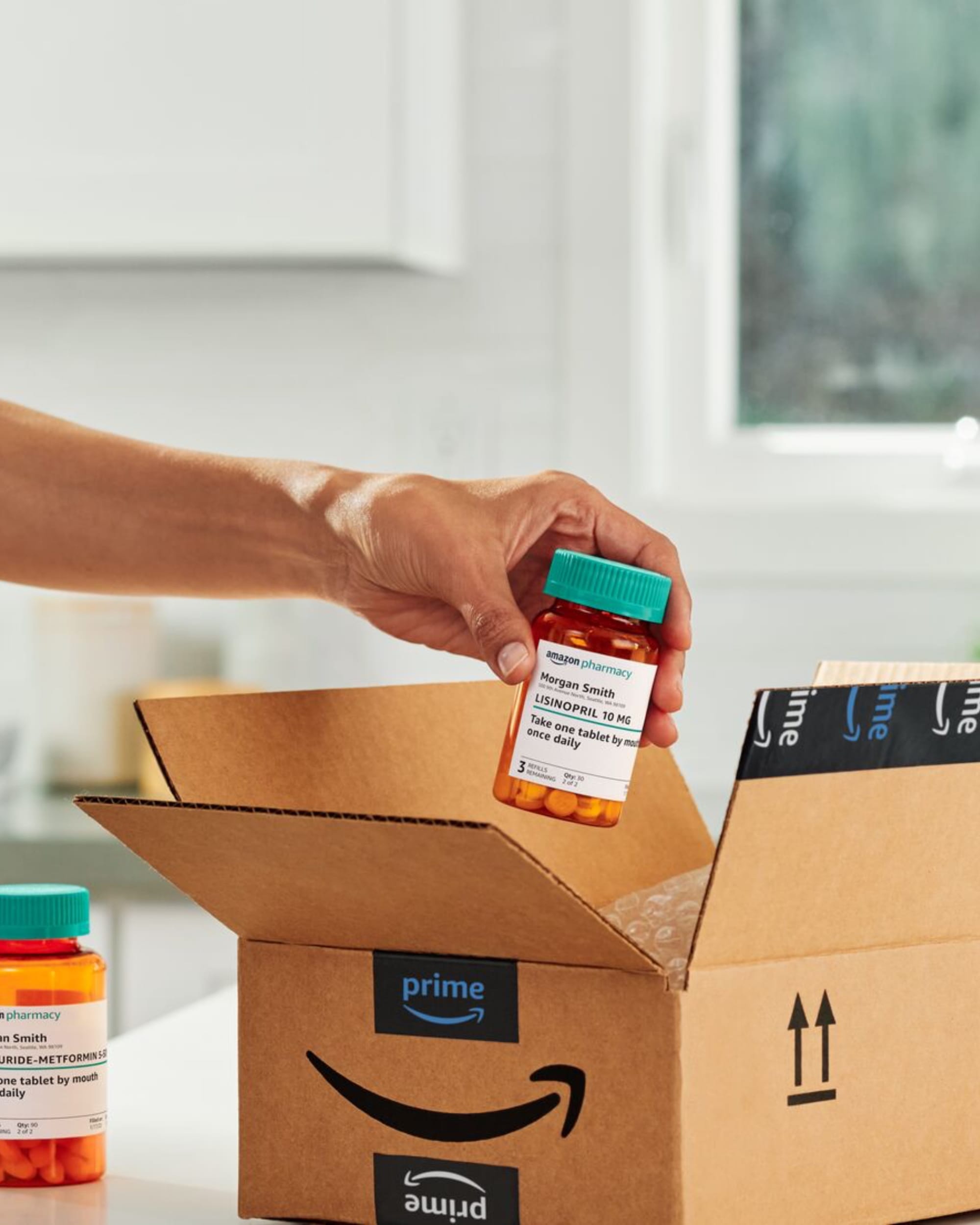 Hand unboxing Amazon Pharmacy prescription delivery with Prime-branded packaging and medication bottles