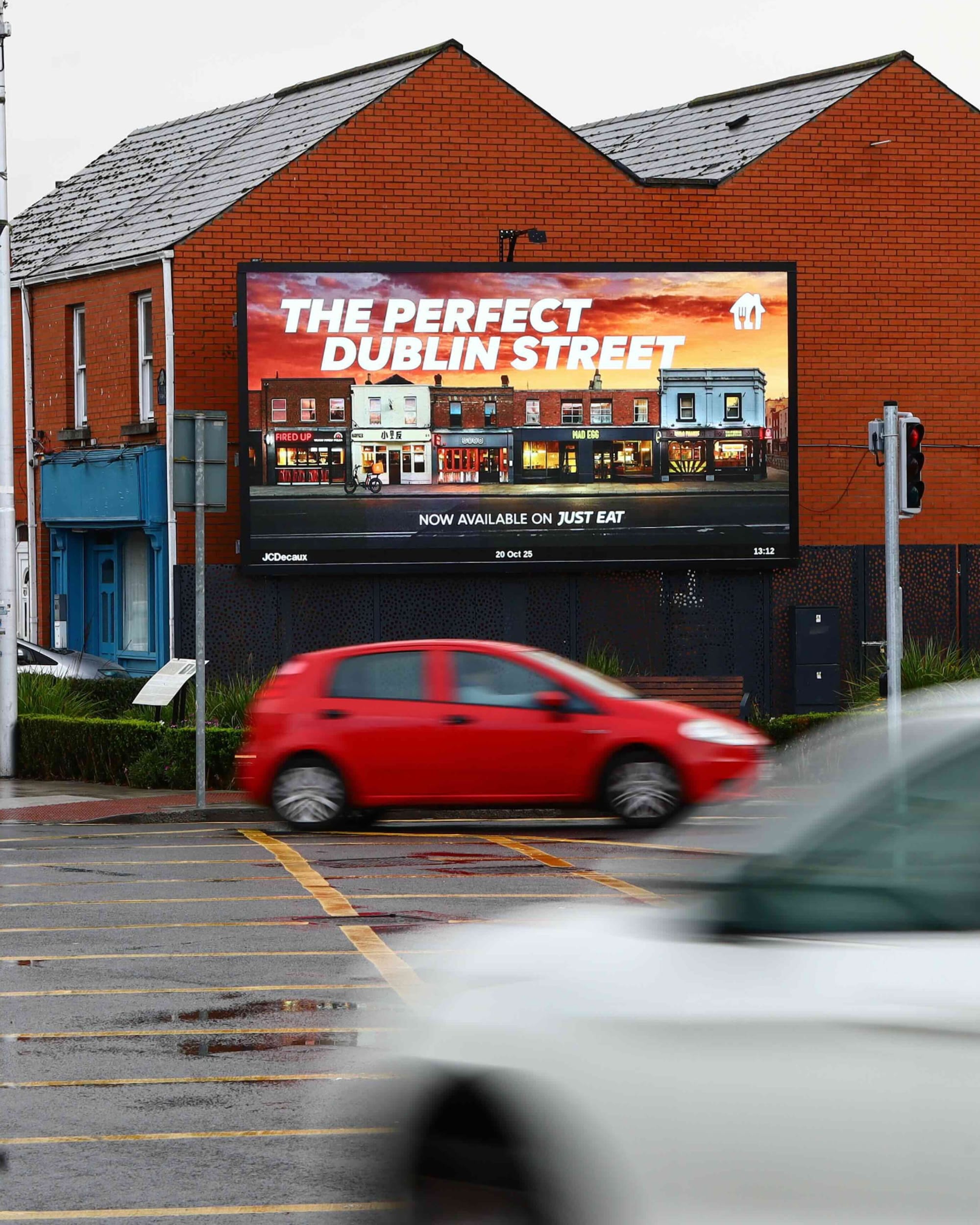 JCDecaux digital billboard on a Dublin street, cars passing, programmatic DOOH advertising in Ireland.