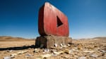 YouTube Play button monument in a desert surrounded by cancelled subscription receipts.