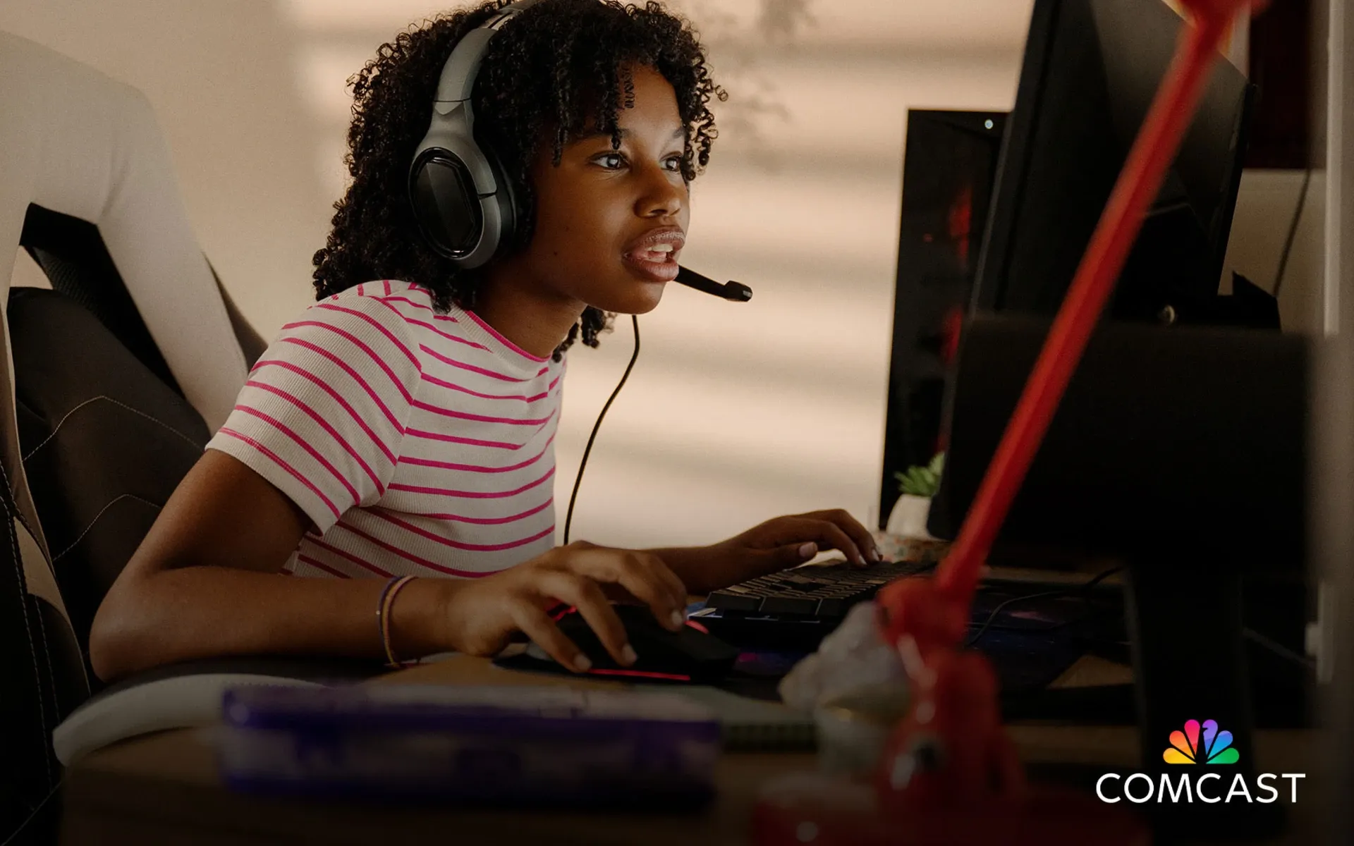 A person wearing a striped shirt and headset plays a game, highlighting Comcast's new low-latency internet tech