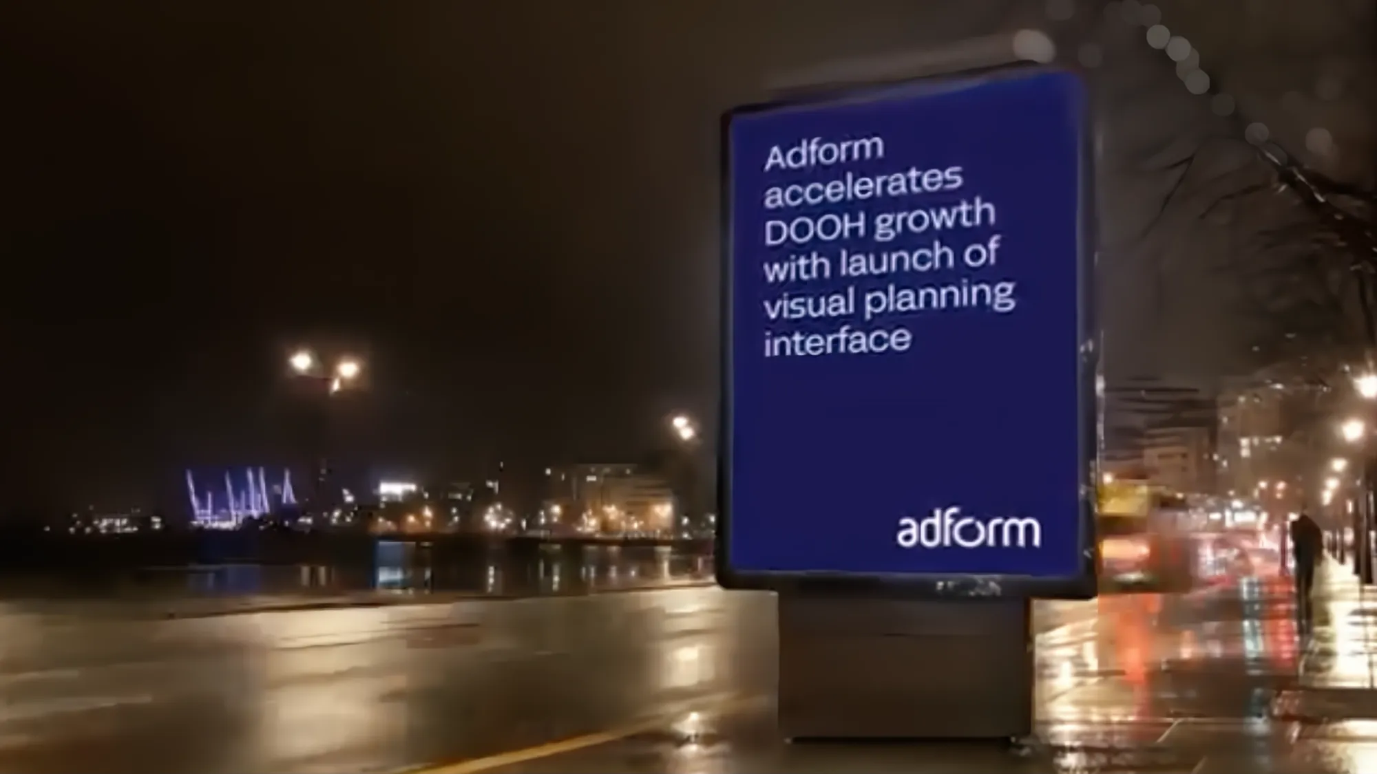 Digital billboard displays Adform's DOOH visual planning interface launch announcement in urban nighttime setting