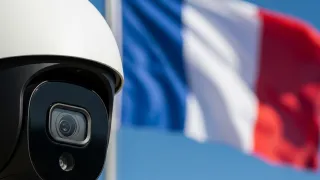 Modern surveillance camera with French flag backdrop highlighting CNIL's ruling on AI age estimation systems.