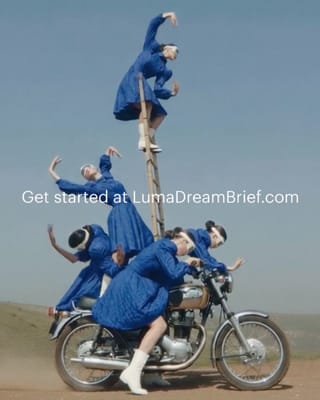Performers in blue dresses stack acrobatically on a motorcycle in a desert landscape.