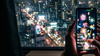 Hand holds phone with crystal gift overlays during YouTube vertical live stream, Jakarta night