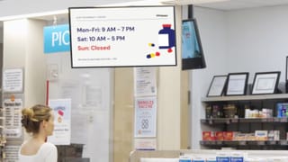 Digital screen displaying pharmacy hours inside a grocery store retail media network.