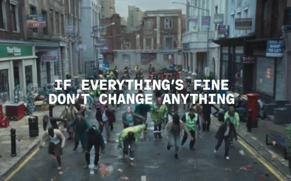 Coinbase's "Everything Is Fine" ad shows UK street scene with workers dancing amid urban decay and chaos.