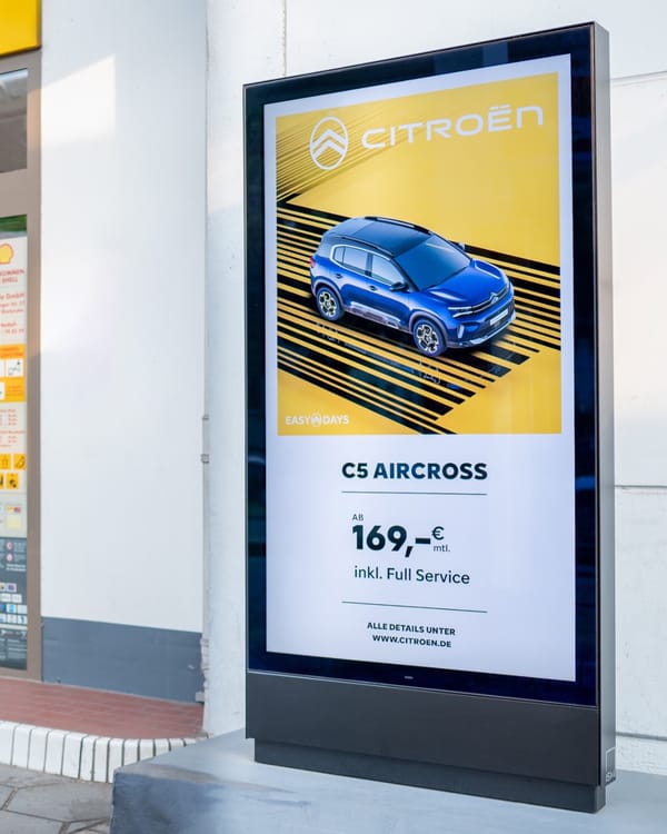 Digital DOOH screen displays Citroën automotive advertisement at German Shell gas station forecourt.