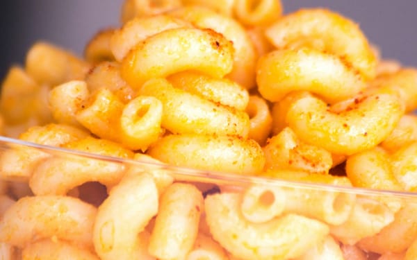 Close-up of golden macaroni and cheese in a glass bowl showing texture and cheese sauce coating