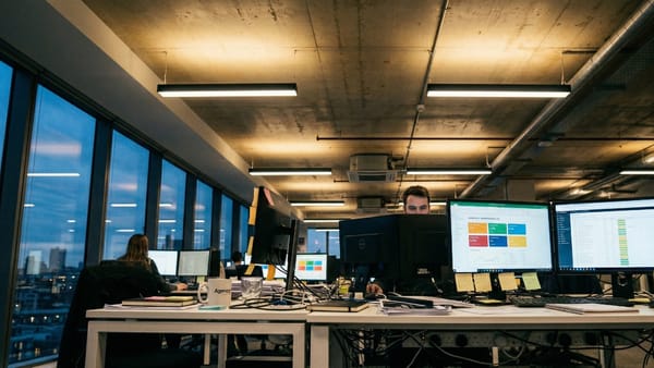 Agency workers manage multiple campaign dashboards late into the evening at a digital ad agency.