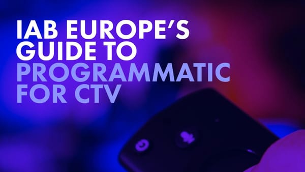 Hand holding TV remote control in blue and purple light, IAB Europe CTV programmatic guide.