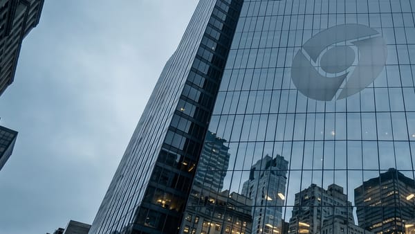 Glass tower reflects trapped city buildings beneath Chrome logo.
