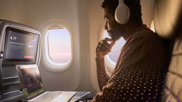 A passenger uses a laptop on a Delta flight with Amazon Leo Wi-Fi, seat 21F visible on the seatback screen.
