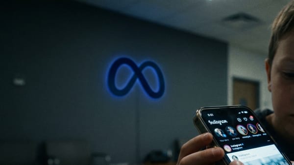 Child scrolling Instagram on smartphone with glowing Meta logo on wall in dark room.
