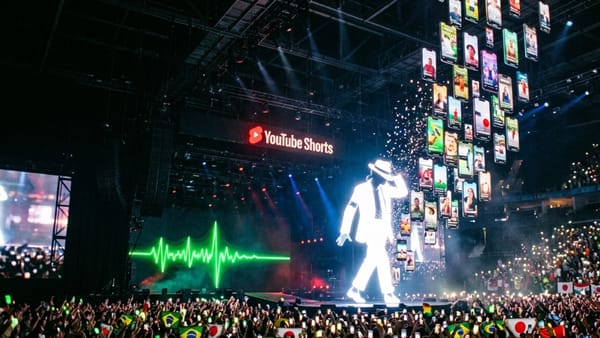 Michael Jackson hologram on stage with YouTube Shorts logo and global flags in the crowd